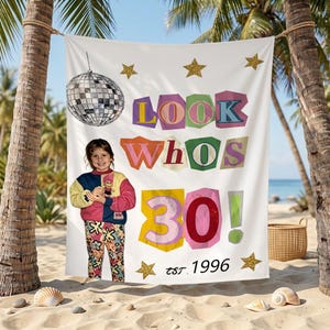 May include: A white rectangular tapestry featuring a disco ball, gold stars, and the colourful text LOOK WHOS 30! est. 1996. The design includes a photographic image of a person wearing a colour-blocked sweatshirt and patterned trousers.