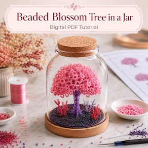 May include: A beaded blossom tree inside a clear glass jar with a cork lid and wooden base. The tree has a purple trunk and pink beaded foliage, sitting on a bed of dark purple beads with small red and purple beaded accents inside the jar.
