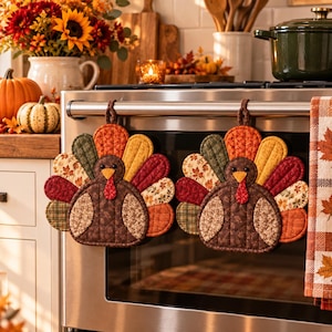 Puede incluir: Dos agarraderas de tela acolchada con forma de pavo, con cuerpos marrones, alas estampadas y plumas de cola coloridas y texturizadas en tonos naranja, amarillo, rojo y verde, colgadas del asa de un horno de acero inoxidable.