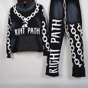 Puede incluir: Conjunto de sudadera con capucha y pantalón de chándal negros con cadenas blancas y gráficos de texto. La sudadera con capucha presenta un diseño de cadena alrededor de la capucha y los hombros, con las palabras "RIGHT PATH" en la parte delantera.