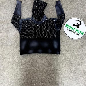 Può includere: Una tazza di ceramica bianca con manico nero e la scritta "But First, Coffee" in grassetto nero. La tazza è appoggiata su una superficie di legno. La tazza è alta circa 10 cm.