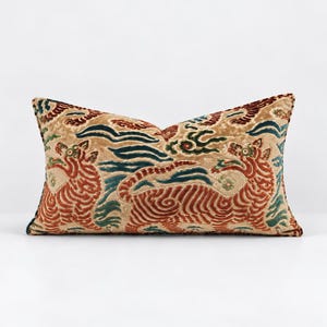 May include: A rectangular throw pillow featuring a tan velvet base with a raised, textured pattern of two tigers in rust orange, accented by swirling cloud motifs in deep teal and dark brown. The design covers the entire front surface.