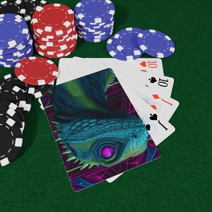 Op de afbeelding: Speelkaarten met een fantasie hagedis ontwerp, uitgespreid op een groene ondergrond. Pokerchips in rood, zwart en blauw zijn rond de kaarten gestapeld. De kaarten tonen het nummer 10 en de kleuren harten, schoppen en ruiten.