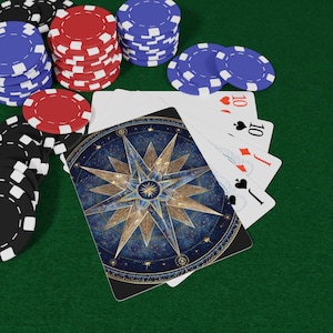 May include: A deck of playing cards with a celestial compass design, alongside stacks of red, blue, and black poker chips. The cards show the ten of hearts, diamonds, spades, and clubs. The background is a green felt surface.