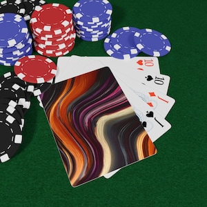 May include: A deck of playing cards with a colorful abstract design, next to poker chips in red, black, and blue. Four playing cards show the number 10 with different suits. The background is a green felt surface.