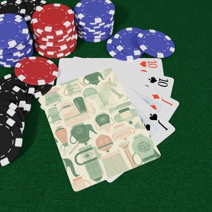 Pode incluir: Fichas de pôquer pretas, vermelhas e azuis cercam um baralho de cartas. As cartas mostram o número dez e um padrão decorativo de bules e xícaras. A cena é ambientada em uma superfície de feltro verde.