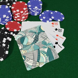 Puede incluir: Una configuración de juego de póquer con cartas y fichas de póquer. Las cartas están abanicadas, mostrando el diez de corazones, diamantes, picas y tréboles. Pilas de fichas de póquer rojas, azules y negras están dispuestas alrededor de las cartas sobre una superficie verde.