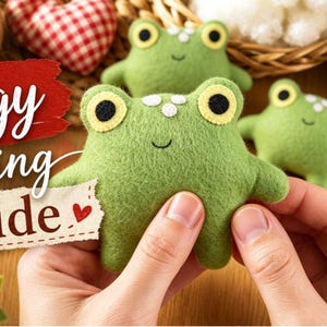 Op de afbeelding: Drie groene vilten kikkerknuffels met zwarte en gele ogen en witte stippen op hun hoofd. Een rode textuurbanner met de witte tekst Froggy sewing Guide, vergezeld van een klein rood hartje op een apart wit papieren label.