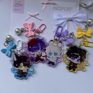 May include: Four acrylic keychains featuring illustrated anime-style characters, each attached to a colored lobster clasp, a small white pearl bead, and a decorative bow. The characters have distinct hair colors and outfits, with clear acrylic backgrounds.