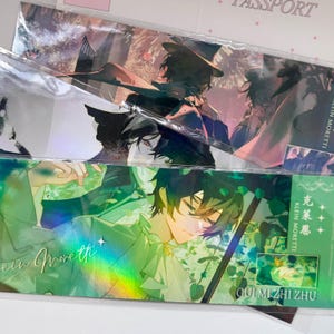 May include: Two rectangular bookmarks featuring anime-style illustrations of a character named Klein Moretti. The top bookmark shows a dark-haired figure in a hat, while the bottom one displays a green-toned scene with text in English and Chinese.