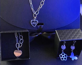May include: A silver-toned necklace featuring a mixed-link chain and a heart-shaped pendant with the word love inscribed. Two small black boxes contain a second heart necklace and a pair of earrings with flower and butterfly charms.