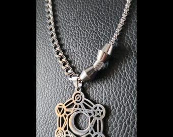 May include: A silver-toned metal necklace featuring a curb chain and a pendant with a complex geometric design. The pendant includes a central crescent moon shape surrounded by interconnected lines, circles, and small symbols, with two cylindrical beads.