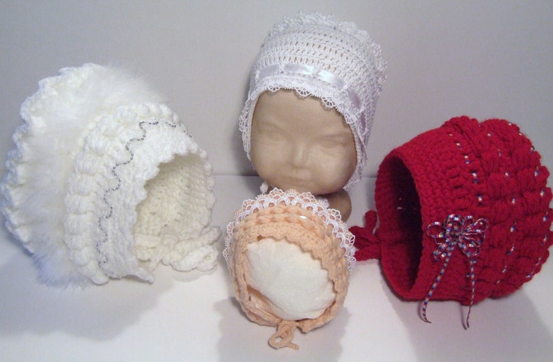May include: Four crocheted baby bonnets in white, peach, and red. The bonnets have different lace trims and embellishments.