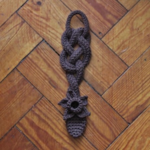 May include: A brown crocheted flower-shaped key chain with a knotted design.