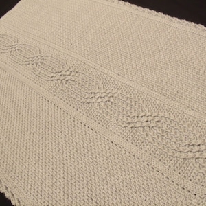 May include: A white crocheted baby blanket with a cable stitch pattern.