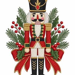 May include: An embroidered nutcracker figure wearing a black hat, red jacket with gold trim, and black boots. The figure is surrounded by green pine needles, holly leaves, and red berries, with a large red ribbon tied at the base of the design.
