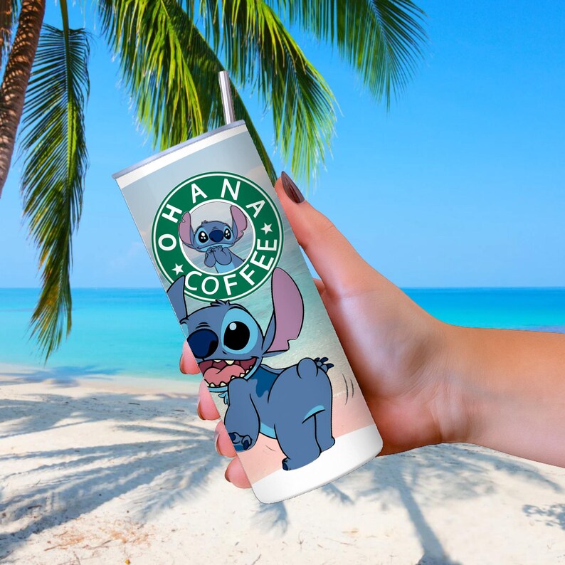 Peut inclure: Un gobelet en acier inoxydable avec un motif de personnage de dessin anim&eacute;. Le gobelet a un fond bleu clair avec les mots "OHANA COFFEE" dans un logo circulaire. Le personnage est bleu avec de grandes oreilles et une expression espi&egrave;gle.