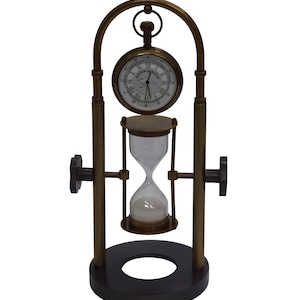 May include: A brass-toned metal desk clock and hourglass combination set on a dark circular base. The clock face features Roman numerals and the text "AUSTRALIA WATCH" with a kangaroo graphic. The hourglass contains white sand.