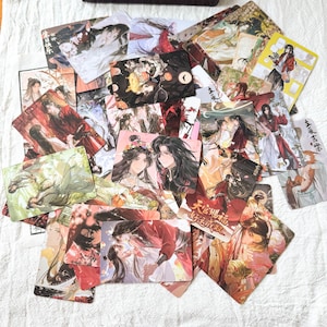 May include: A collection of rectangular cards featuring colourful anime-style illustrations of characters with long dark hair in traditional clothing. The artwork displays various scenes with red, white, and green colour palettes, including Chinese text characters on several of the cards.