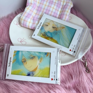 May include: Two clear plastic pouches with white borders designed to resemble Instagram posts. Each pouch contains an anime-style illustration of a character with blue hair and yellow clothing. The text Instagram, 6,688 Likes, and #Nice to meet u are printed on the white borders.