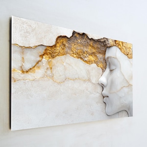 May include: A rectangular wall art piece featuring a profile of a woman's face in white against a backdrop of white and gold textures. The gold accents create a striking contrast, enhancing the artwork's visual appeal. The piece is designed to be mounted on a wall.