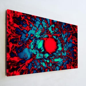 May include: Abstract art print featuring a vibrant composition of red, blue, and green hues. The artwork showcases a central red orb surrounded by swirling patterns, creating a dynamic and eye-catching visual effect. The piece is mounted on a white wall.