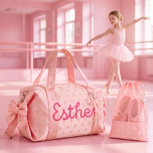 May include: A light pink duffel bag with a polka dot pattern and the name Esther embroidered in dark pink script. The bag features a large side bow, a pearl charm, and a matching pink mesh drawstring bag for ballet slippers.