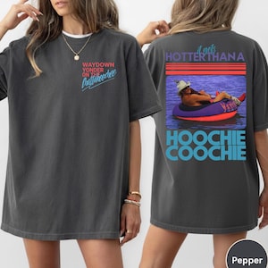 May include: Dark gray t-shirt with the text "WAYDOWN YONDER ON THE Chattahoochee" on the front. The back of the shirt features a graphic of a person in a tube with the text "it gets HOTTER than a HOOCHIE COOCHIE".