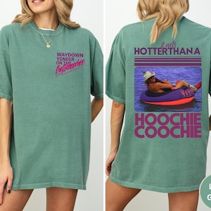 May include: Light green t-shirt with the text "WAYDOWN YONDER ON THE Chattahoochee" in pink and the back of the shirt has the text "it gets HOTTER THANA HOOCHIE COOCHIE" with a picture of a person in a tube.