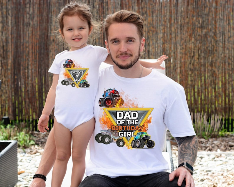 Puede incluir: Un padre y su hija con camisetas blancas a juego. Las camisetas presentan un dise&ntilde;o de monster truck con el texto "DAD OF THE BIRTHDAY GIRL" y "EMILY'S 3rd JAM". El fondo es una valla de madera.