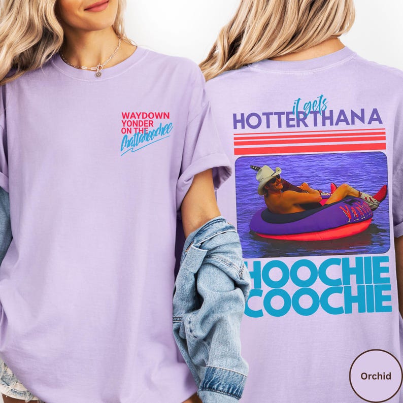 May include: Orchid-colored t-shirt with text on the front and back. The front says "Waydown Yonder on the Chattahoochee" in red and blue. The back features a graphic of a person in a tube and the words "It gets hotter than a Hoochie Coochie."