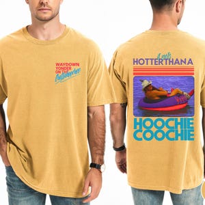 May include: Mustard-colored t-shirt with the text "WAYDOWN YONDER ON THE Chattahoochee" on the front. The back features a graphic with the text "it gets HOTTERTHANA HOOCHIE COOCHIE".
