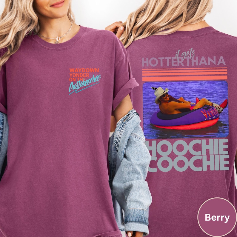 May include: Berry-colored t-shirt with the text "WAYDOWN YONDER ON Chattahoochee" on the front. The back of the shirt features a graphic of a person floating in a tube with the text "it gets HOTTER THANA HOOCHIE COOCHIE".