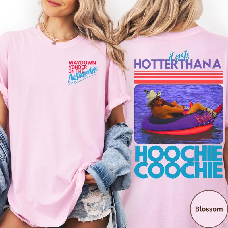 May include: A light pink t-shirt with the text "WAYDOWN YONDER ON THE Chattahoochee" on the front. The back of the shirt features a graphic of a person in a tube with the text "it gets HOTTER THANA" and "HOOCHIE COOCHIE".