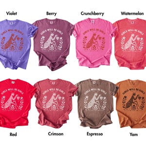 May include: Eight short-sleeved t-shirts in violet, berry, crunchberry, watermelon, red, crimson, espresso, and yam colours. Each shirt features a graphic of a praying mantis with the text "GIRLS WILL BE GIRLS" printed in a contrasting colour.