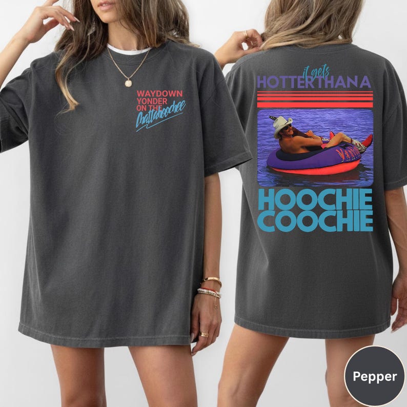 May include: Dark gray t-shirt with the text "WAYDOWN YONDER ON THE Chattahoochee" on the front. The back of the shirt features a graphic of a person in a tube with the text "it gets HOTTER than a HOOCHIE COOCHIE".