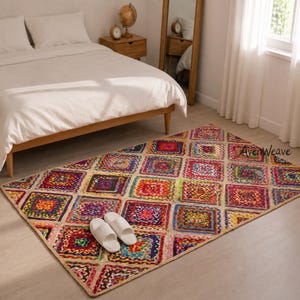 May include: A rectangular area rug featuring a vibrant patchwork of multicolored square motifs in shades of red, blue, yellow, and purple, bordered by natural jute fibers. A pair of white slip-on house slippers rests on the rug's surface.