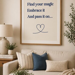 以下が含まれることがあります： 「Find your magic, Embrace it, And pass it on...」のテキストとハートのシンボルが描かれた額入りのプリント。装飾的な枕とスローブランケットが置かれたソファの上に飾られています。木製のコーヒーテーブルには、キャンドルと花瓶が置かれたトレイがあります。