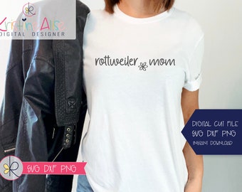 May include: A white t-shirt with the text "rottweiler mom" and a small flower graphic. The text is in black and the flower is in gray. The t-shirt is being worn by a person. The image also includes a black leather jacket and a blue background.