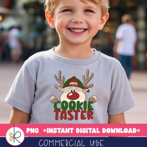 May include: A child wearing a gray t-shirt with a cartoon reindeer wearing a Santa hat and the text "Cookie Taster".