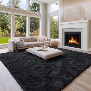 May include: A large, rectangular, solid black area rug with a thick, plush, shaggy texture covering the floor. The rug features a deep, uniform charcoal black color and a soft, high-pile surface that creates a dense, fuzzy appearance throughout.