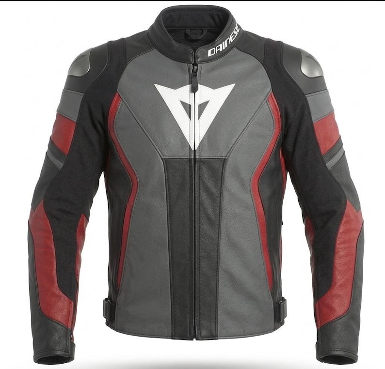 May include: A black, gray, and red motorcycle jacket with the brand name "Dainese" on the collar. The jacket features a white triangle logo on the chest and silver shoulder protectors. The design includes red accents on the sleeves and sides.