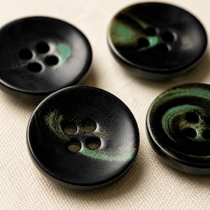May include: Four round buttons with a smooth black finish and distinct teal green marbled accents. Each button features a classic four-hole design in the center, with a slightly concave surface and a raised outer rim, showcasing a dark color palette.
