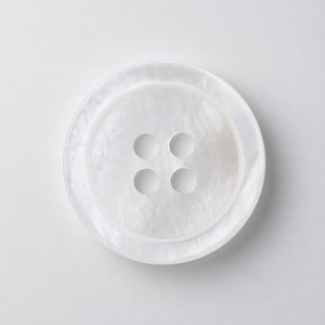 Peut inclure: Un bouton rond blanc à quatre trous avec une finition nacrée et scintillante. Le bouton présente un bord extérieur légèrement surélevé et une texture de surface lisse et brillante qui reflète la lumière, créant des nuances subtiles.