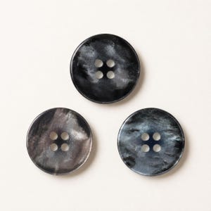 May include: Three circular buttons arranged in a triangle formation. Each button features a four-hole centre and a marbled, swirling pattern in shades of dark grey, black, and silver with a smooth, polished finish on the surface.