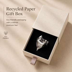 May include: A silver ring shaped like a knight's helmet resting inside a beige recycled paper gift box with a black velvet insert. The box features the text Recycled Paper Gift Box, Eco-friendly packaging with a refined premium feel, and ECO FRIENDLY.