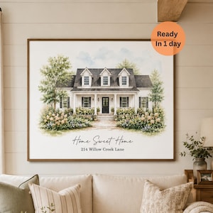 Pode incluir: Uma impressão emoldurada em estilo aguarela de uma casa branca de dois andares com telhado escuro, alpendre e vegetação verde. O texto "Home Sweet Home" e "214 Willow Creek Lane" está impresso em preto abaixo da ilustração da casa.