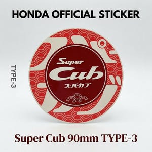 May include: A circular Honda official sticker, Type-3, featuring a dark red center with the white text Super Cub and Japanese characters. The border displays a red and white wave pattern. The text Super Cub 90mm TYPE-3 is visible below.