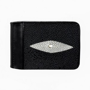 Puede incluir: Cartera de cuero negro con un distintivo diseño de raya blanca. La cartera presenta una superficie negra texturizada con un acento central en forma de diamante blanco. El diseño incluye un pequeño detalle circular en el centro del acento blanco.