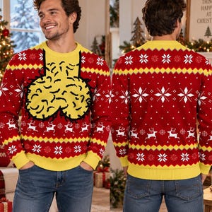 May include: A red and yellow long-sleeve knit jumper featuring a graphic of two yellow textured shapes outlined in black on the front. The jumper has a repeating pattern of white snowflakes and white reindeer across the chest and sleeves.